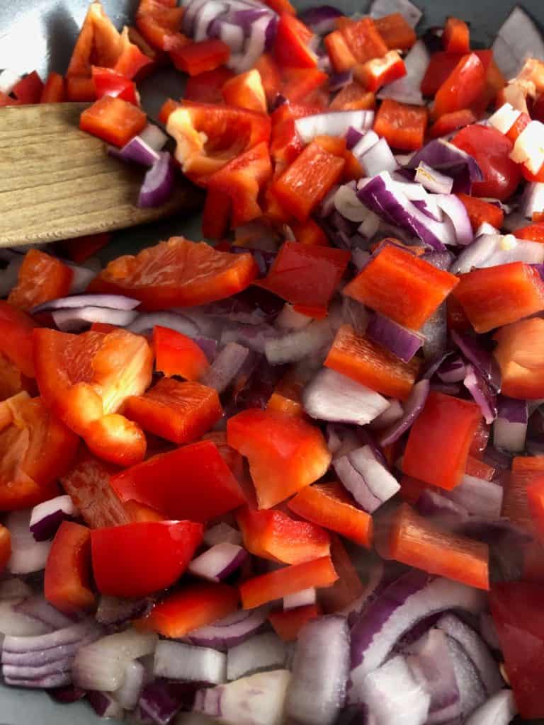 red onions and peppers in frying pan