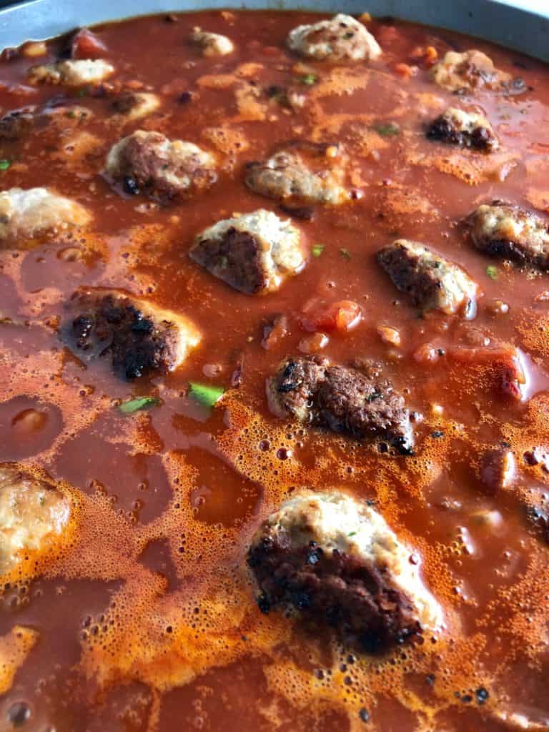 pork meatballs with spaghetti simmering in pan