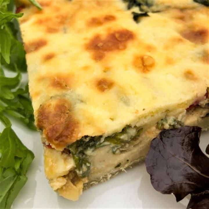 slice quiche on plate with salad
