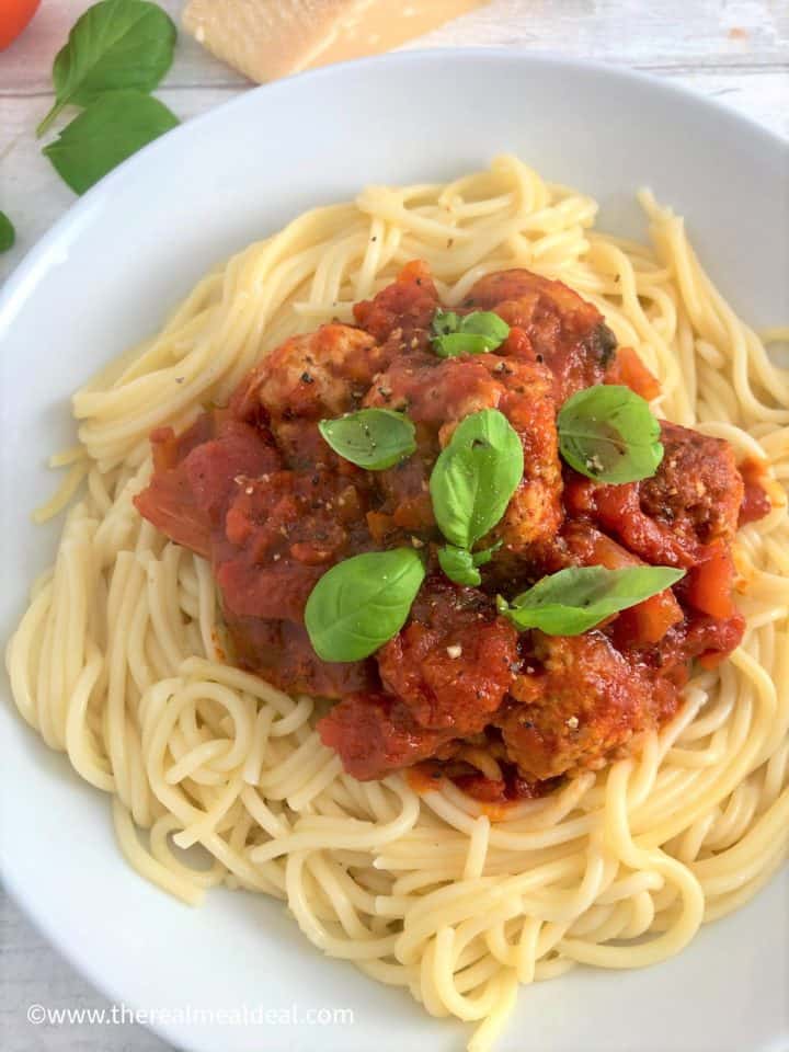 pork meatballs with spaghetti in tomato sauce topped with fresh basil