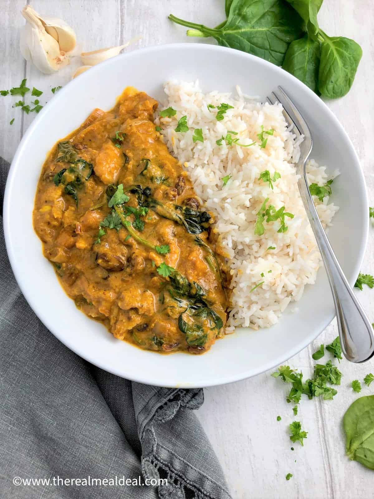 chicken korma in bowl with rice topped fresh coriander