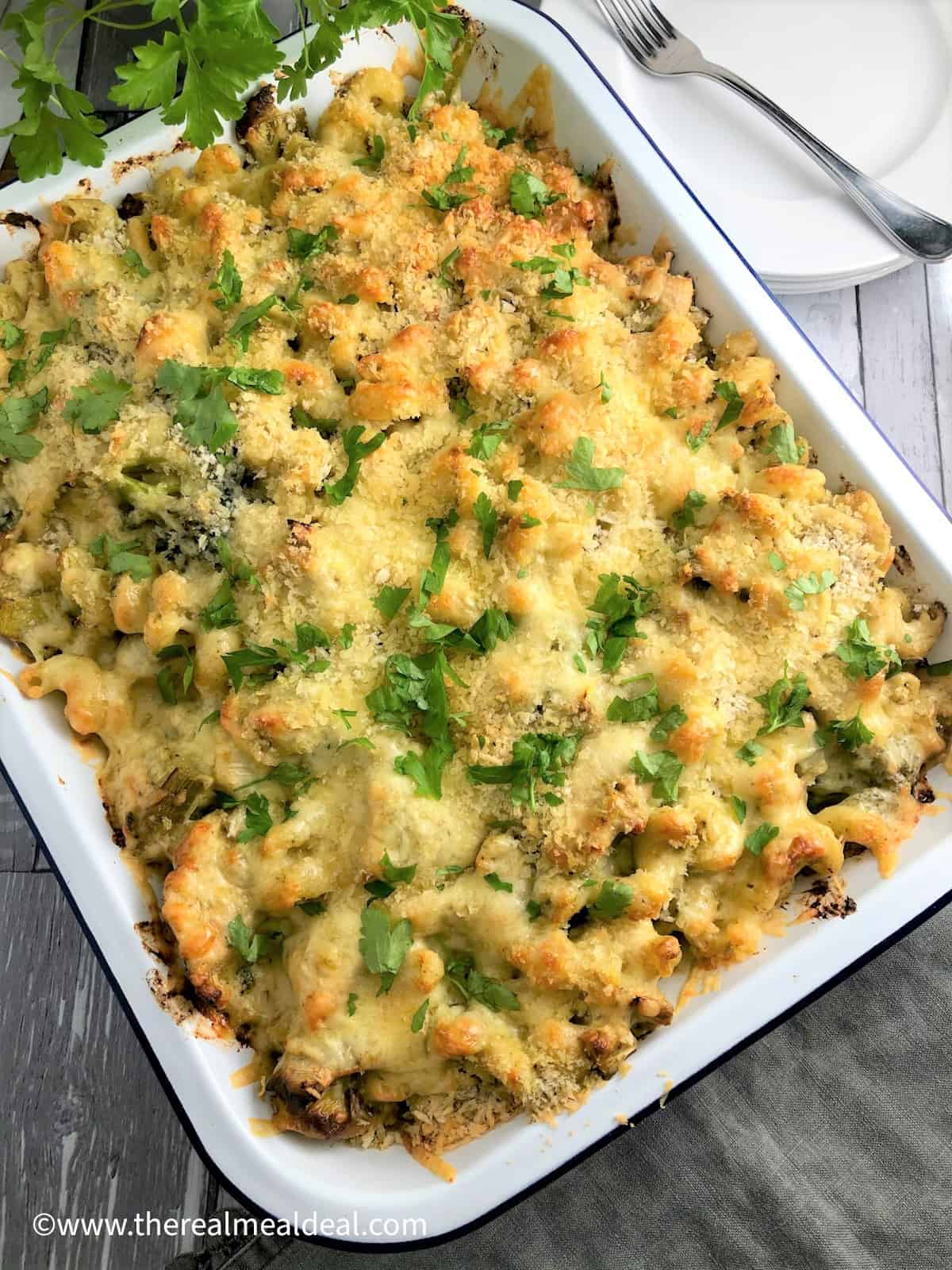 Chicken pasta bake in tray topped with fresh parsley leaves
