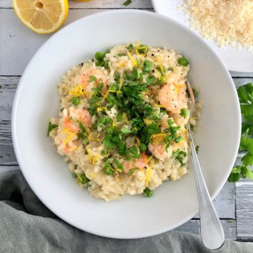 prawn and pea risotto in bowl topped with lemon zest and fresh parsley