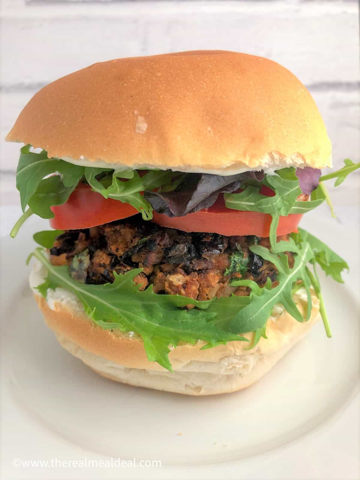 spicy bean burger in bun with rocket sliced tomato