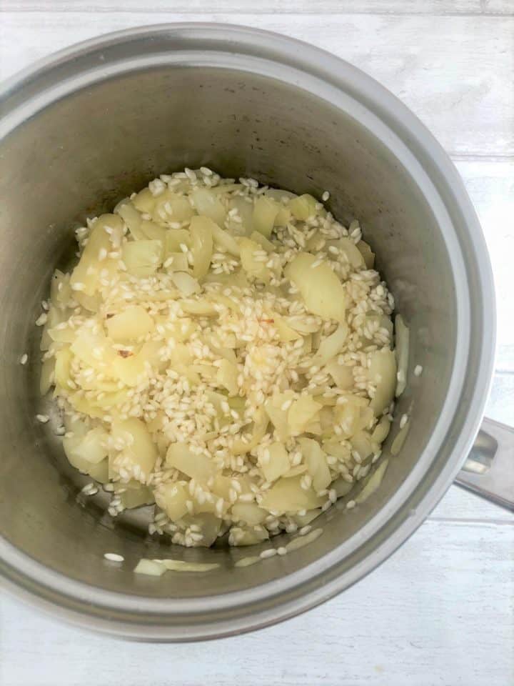 diced onion and risotto rice frying in pan