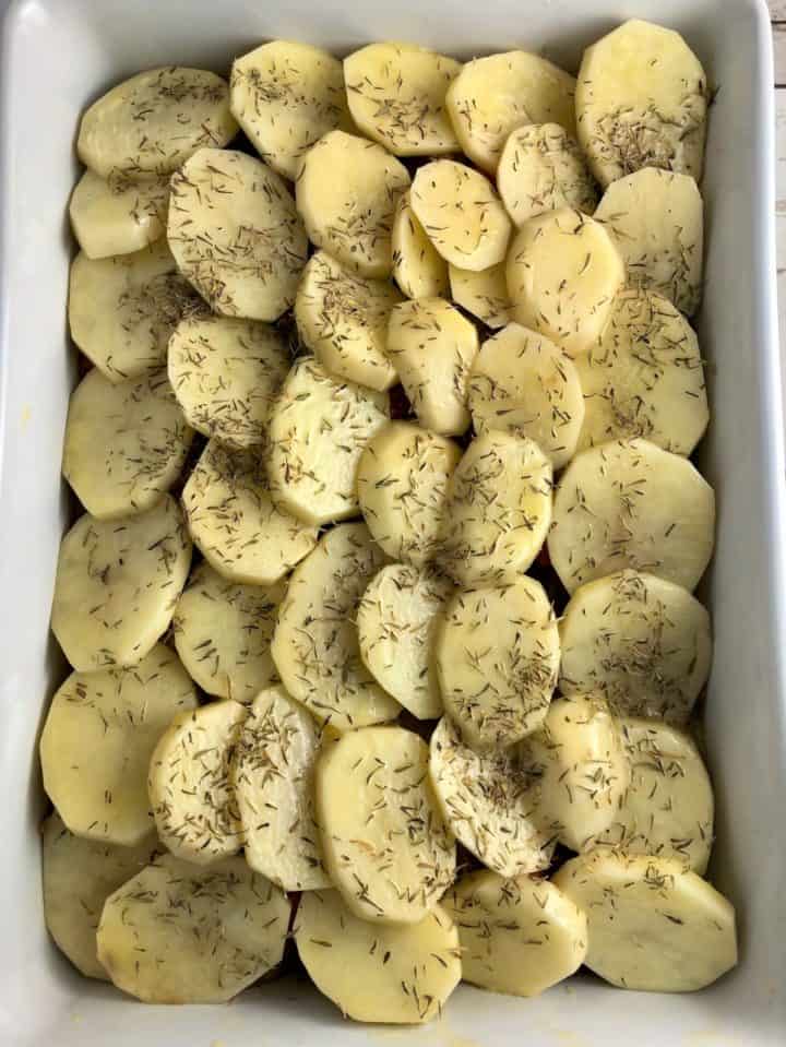 sliced potato on hot pot brushed with butter and sprinkled with thyme leaves