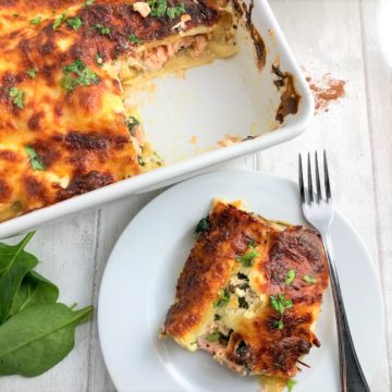 salmon and spinach lasagne in tray with separate slice on plate