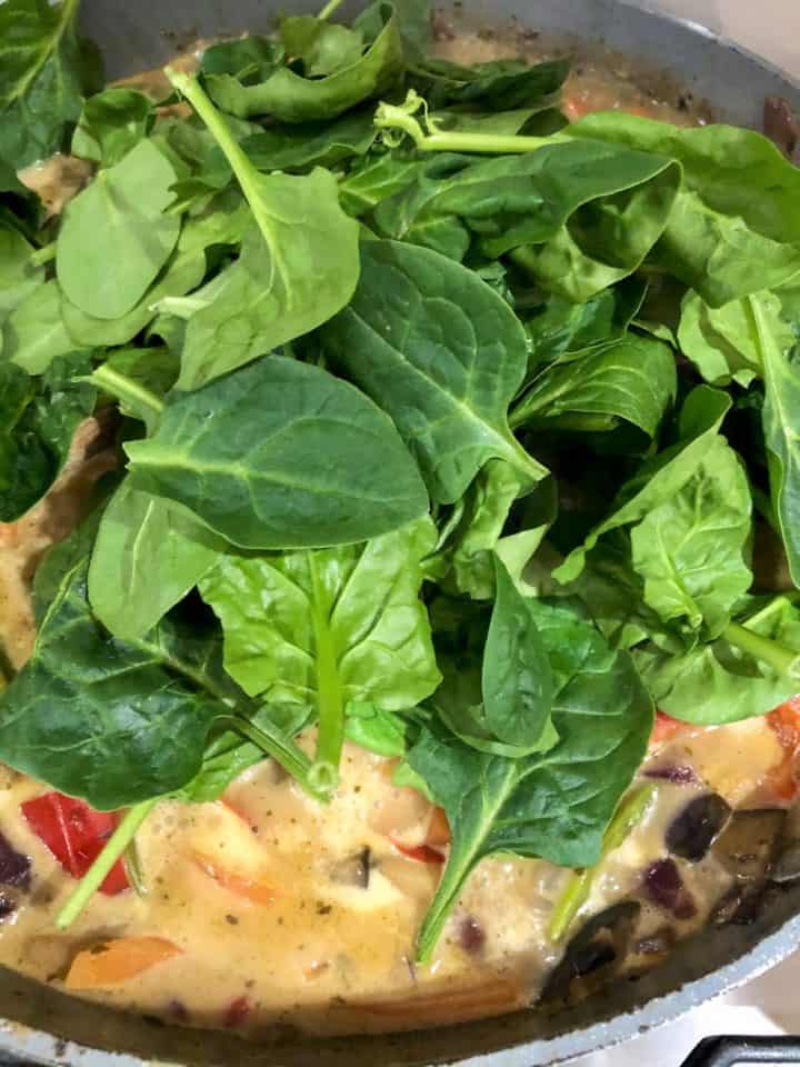 fresh spinach leaves added to vegetable thai green curry