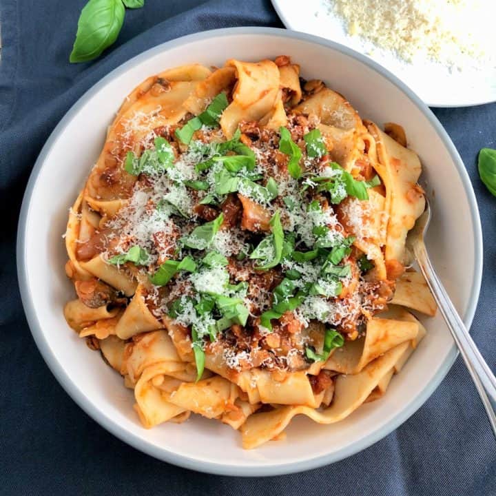 mushroom and lentil ragu served on papadelle pasta topped with fresh basil leaves and parmesan cheese plate parmesan cheese to side
