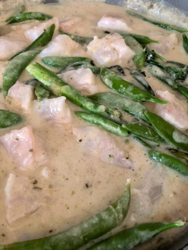 white fish chunks added to thai green curry sauce with sugar snap peas and tenderstem broccoli
