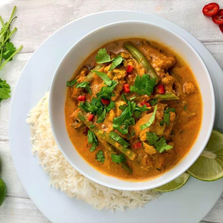 creamy fish curry with coconut milk topped with fresh corainder leaves and served with white rice and lime wedges