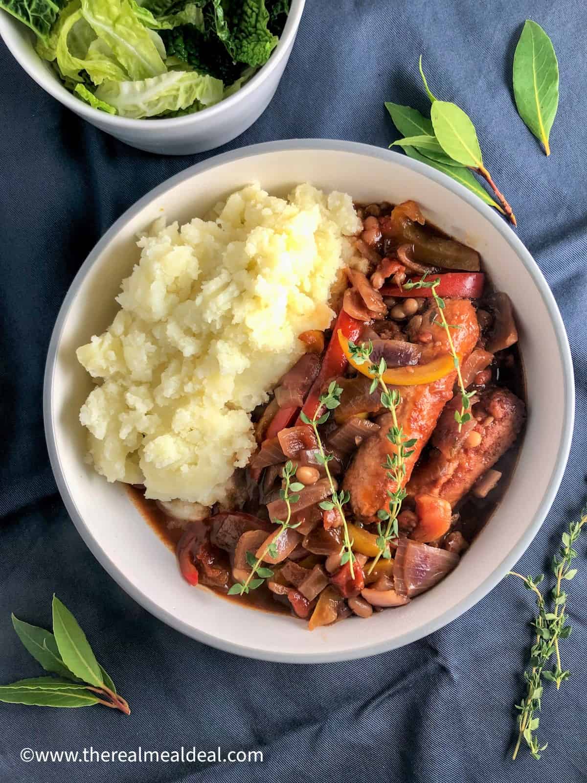 Vegetarian sausage casserole served with mashed potato in a dish topped with fresh thyme