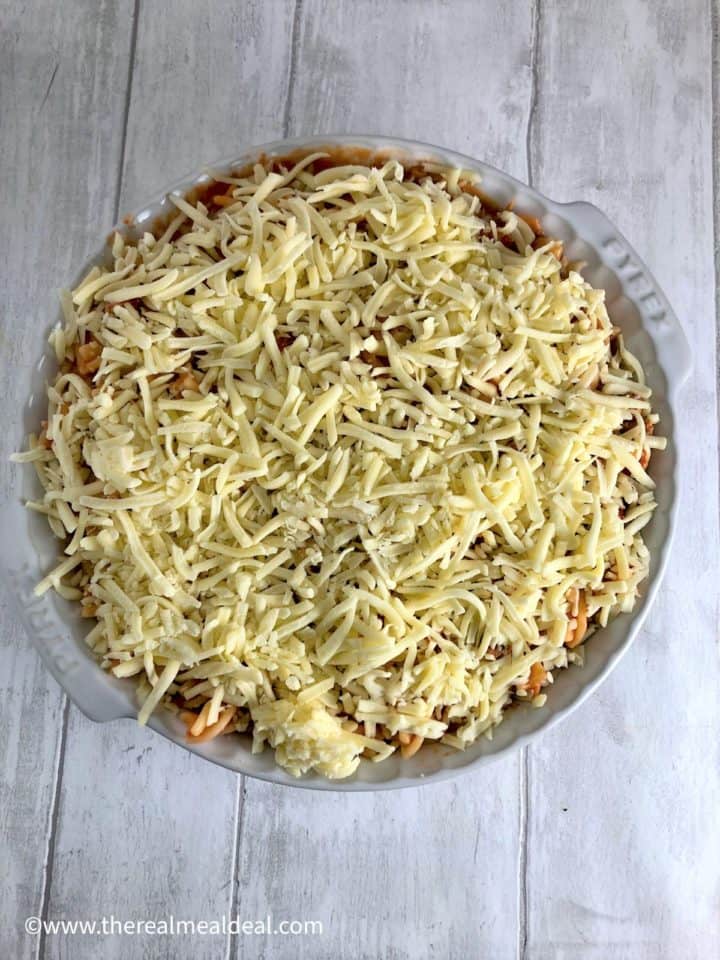 tuna pasta bake assembled in oven proof dish and topped with grated cheese