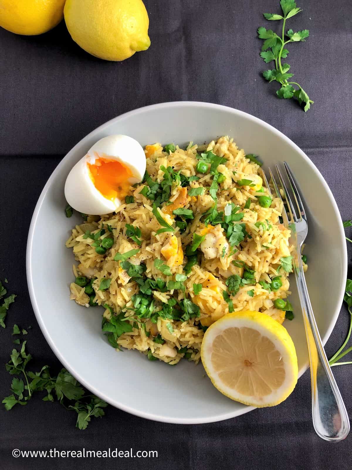 smoked haddock kedgeree with boiled egg and lemon half in bowl topped with fresh parsley