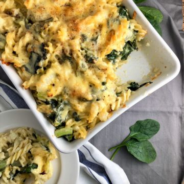 cauliflower and spinach cheese pasta dish with one portion on plate to side.