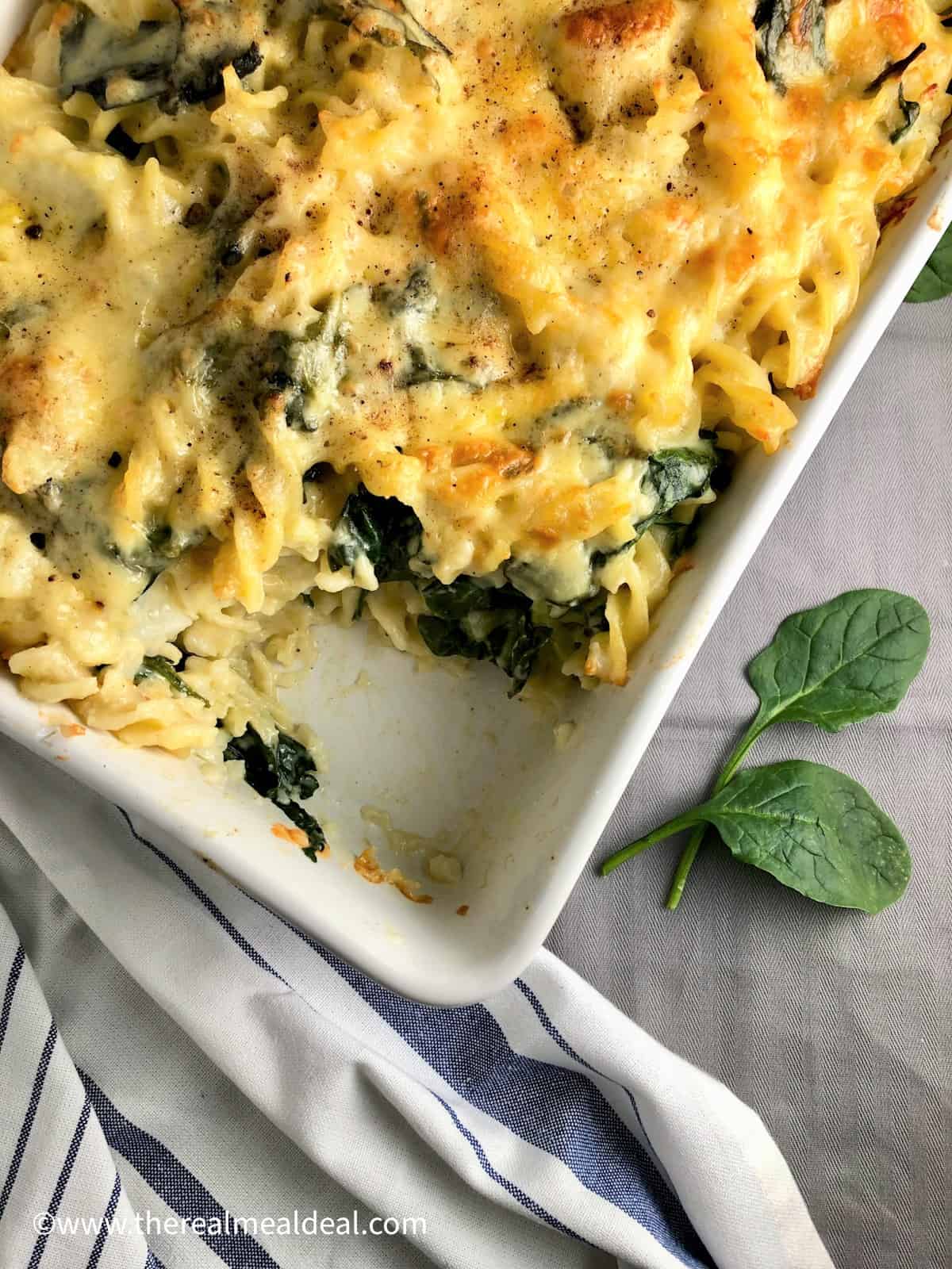 cauliflower cheese pasta bake in casserole dish with portion removed