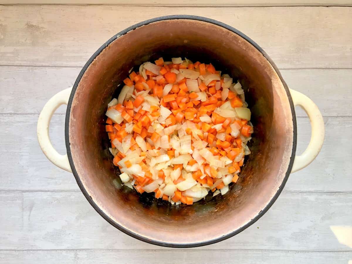 carrots and onions frying in flame proof casserole dish