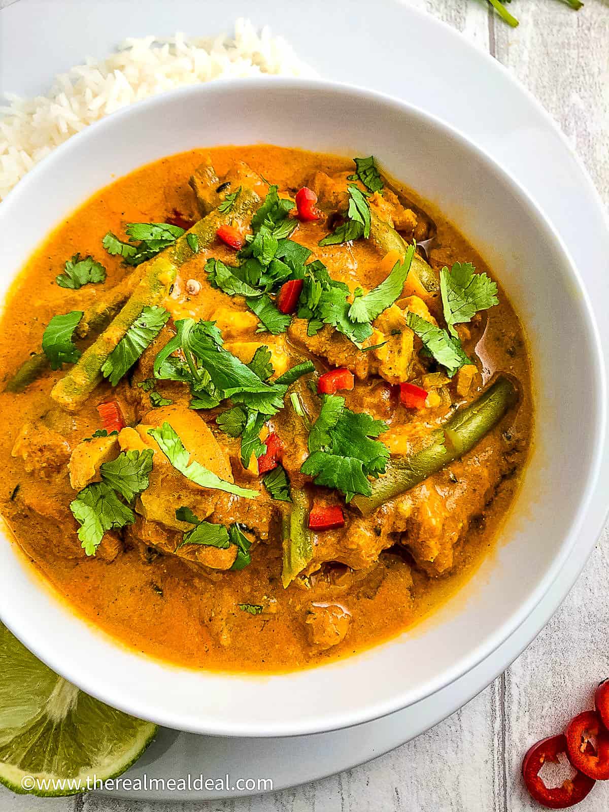 keralan fish curry in a bowl topped with fresh coriander leaves with side of rice