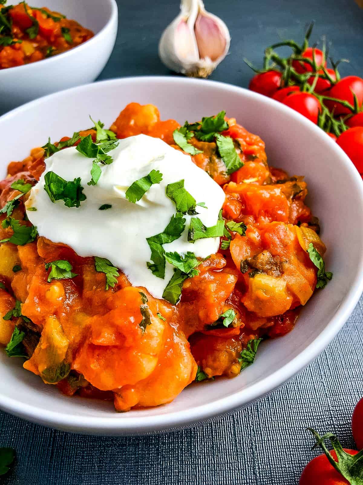 prawns in spicy tomato sauce topped with creme fraiche in bowl