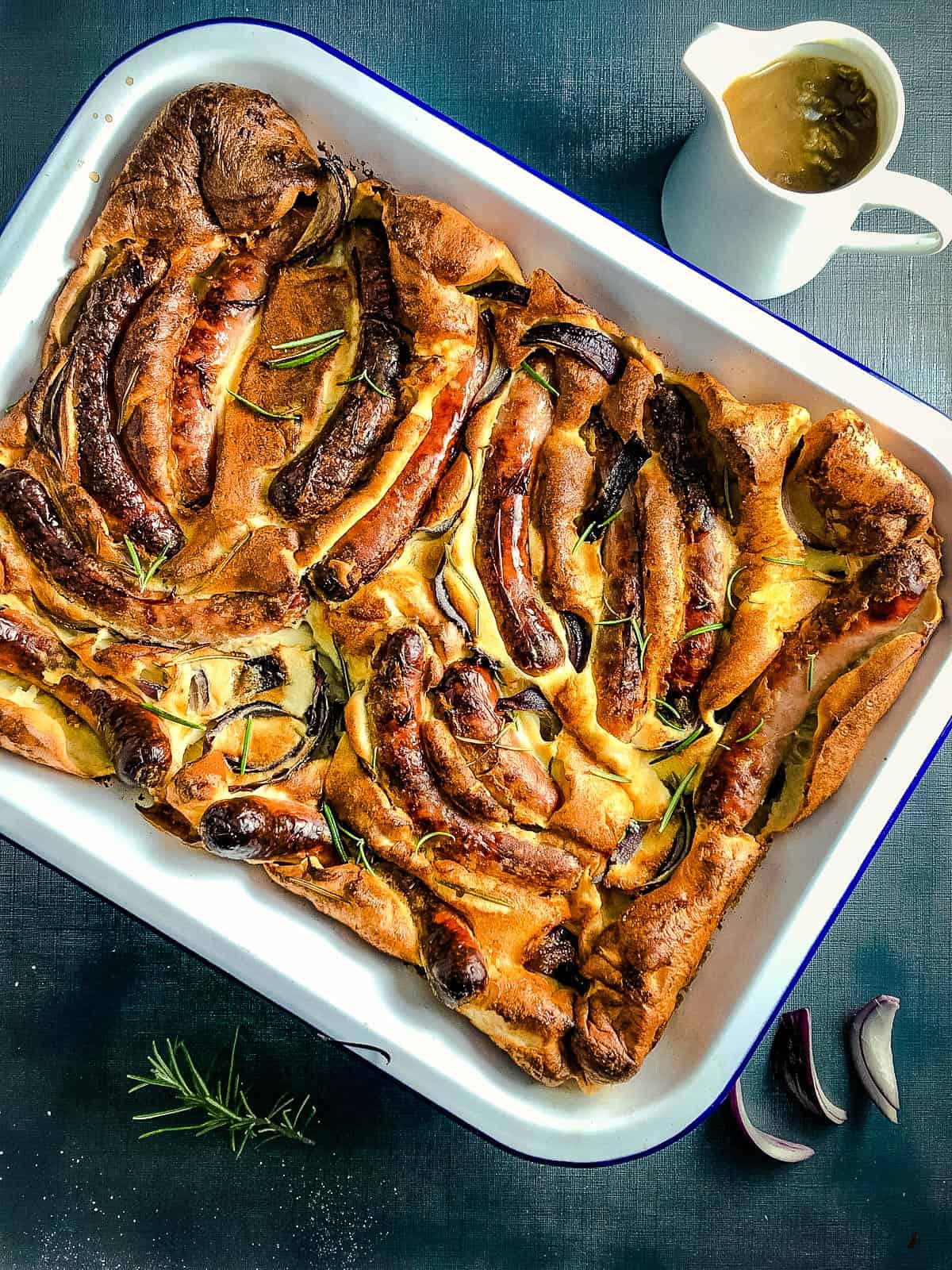 vegan toad in the hole in metal tray with onion gravy to side