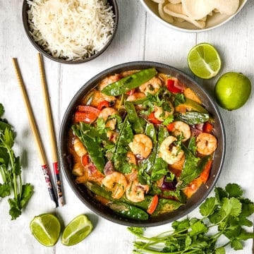 Prawn red thai curry with side of rice and limes and topped with coriander leaves.
