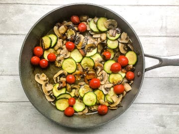garlic and tomatoes added to mushrooms and courgette in pan