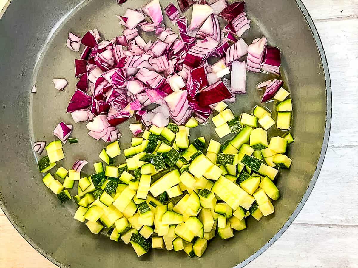 frying pan with diced courgette / zucchini and red onion